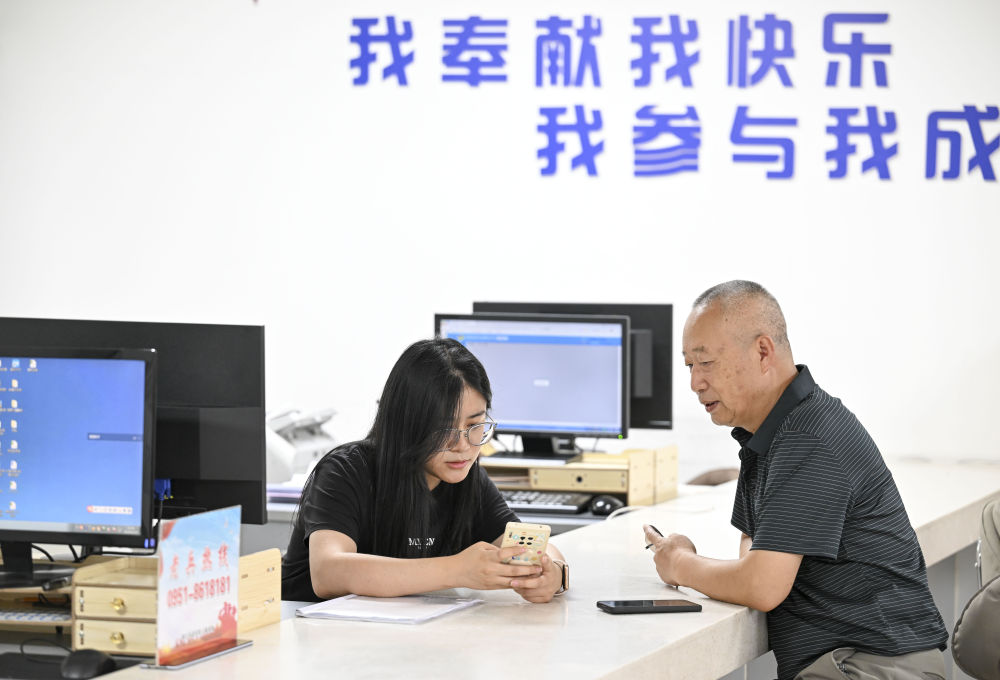 2024年6月20日，在寧夏銀川市金鳳區(qū)長城花園社區(qū)黨群服務(wù)中心，工作人員幫助居民辦理業(yè)務(wù)。圖片來源 新華社